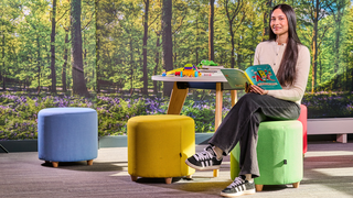 A female student sitting at table with legs crossed holding a book