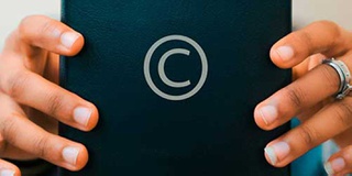 Image of a person holding a book with the copyright symbol on the cover