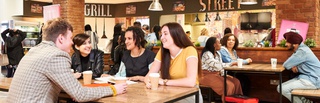 Students sitting at a table in the Millennium City Building Courtyard Kitchen area