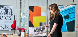 A photo of an art and design student in an art studio, looking at a portfolio of work in a folder