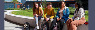 Four students sitting outside Starbucks in the courtyard