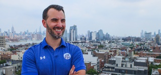 Daniel O Connor photographed wearing a blue sports jersey in front of a city skyline.