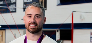 Kristian Thomas photographed wearing a white shirt and an Olympic bronze medal.