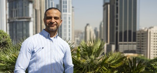 Marwan Nasry photographed against a skyline in Dubai wearing a button-up shirt and jeans.