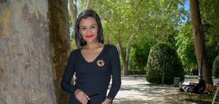 Nathalie Flores standing next to a tree, wearing a black blazer with a multicoloured brooch