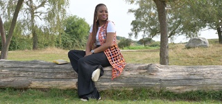 Abi Dare sitting on a log with a book