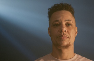 Nate Ethan Watson wearing a white shirt against a backdrop of projected images