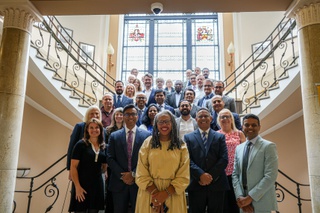 Delegates from the launch event of the clinical trials unit stand in tiers on the steps from reception to the first floor at Wulfruna Building at University of Wolverhampton
