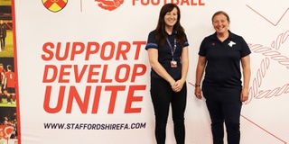 Two women standing in front of a Staffordshire FA banner