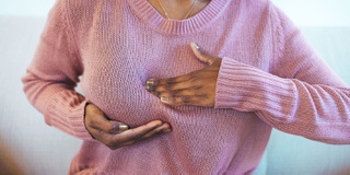 A woman pictured checking her breast for cancer