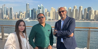 Three notable alumni in Dubai looking at the camera with the skyline behind them