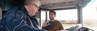 A student showing their id to a bus driver
