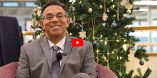 VC Prof Ebrahim Adia, smiling, sitting in front of a Christmas tree