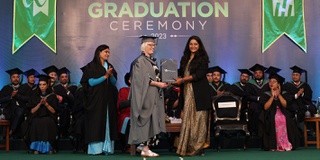 A graduate on stage accepting the Lord Paul Enterprise Award