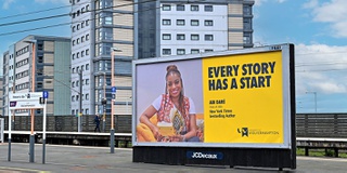 A picture of alumna Abi Dare and the Vice Chancellor in front of her billboard