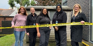 A group of students holding crime scene tape