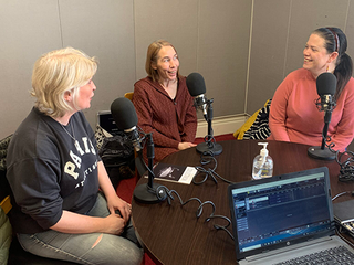 three people in a studio recording a podcast