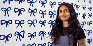 Simmi Sahota Fine Art student in front of degree show piece - a wall mural covered in painted blue bows
