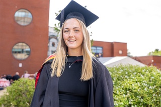 Madi Highfield wearing graduation cap and gown in the courtyard