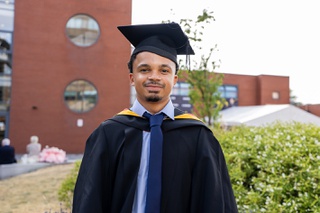 Shaun Johnson wearing graduation cap and gown in the courtyard