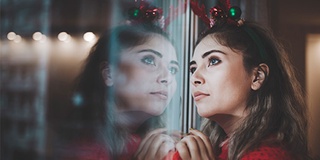Woman dress in festive attire, looking wistfully out of window