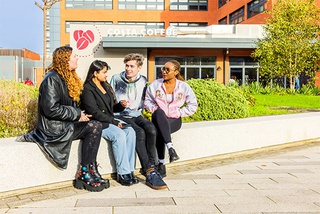 Group of students talking in the City Campus courtyard in front of Costa Coffee