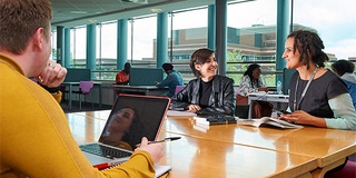 students studying in the library with laptop and books