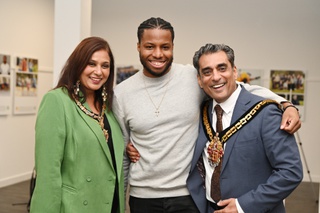A photo of three people with the film-maker in the centre, wearing a grey sweatshirt. On the left is the mayoress wearing green jacket and ceremonial chain and on the right the mayor dressed in a suit and ceremonial chain. All grin widely for the camera.