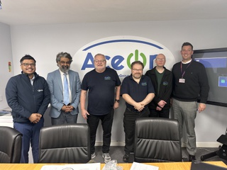 Representatives from Aceon and the University of Wolverhampton line up in front of the Aceon logo on the wall behind in green and blue lettering. The wear business casual clothing and smile for the camera