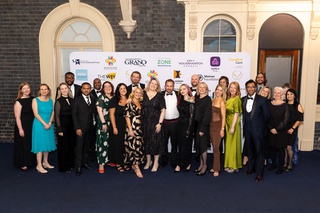 Staff and academics gather together for a group shot, dressed in ball gowns and tuxedos at the awards evening