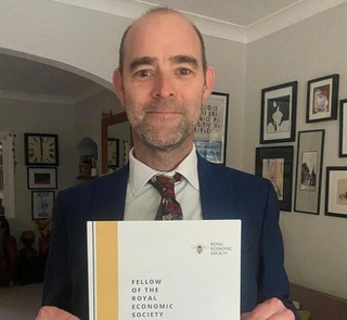 Gavin Simpson holding his award from the Royal Economic Society