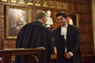 Mudasir Khan is wearing a barrister's gown and shaking hands with a man as he is called to the Bar of England and Wales at Lincoln's Inn in London