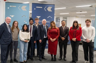 A group of ten people stand in a line in the Student Union. Rt Hon Sir Lindsay Hoyle stands in the centre wearing a dark suit and tie, he is flanked by lecturers and students and the University's Vice Chancellor, Ebrahim Adia.