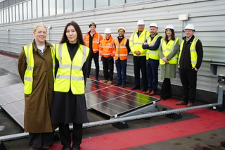 Two representatives from Salix Finance are picture in the foreground wearing high viz jackets in front of solar panels on a roof at Walsall Campus. Pictured behind them are representatives from the University of Wolverhampton and the project contractors VitalEnergi