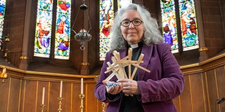 Chaplain Sarah Schofield holding palm crosses and a chocolate cupcake