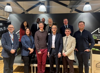 Representatives from West Midlands universities and businesses stand in two rows for a picture at the business event