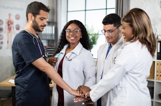 Photo of doctors and nurses putting their hands together