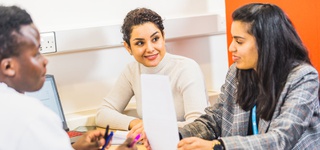 Three students sitting around table talking