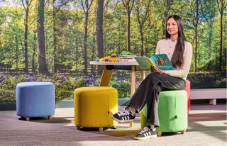 A girl sitting at table in Education building with a book in hand