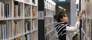 girl in library looking at old paper