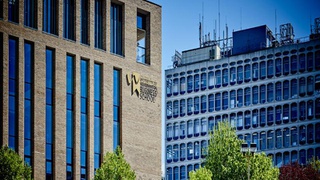 A building with UNIVERSITY OF WOLVERHAMPTON BUSINESS SCHOOL branding on its side against a blue skyline.