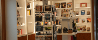 Shelves stocked with artwork, books, pens and postcards