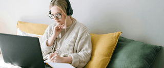 A student wearing headphones looking at a laptop screen