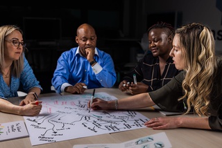 Four students sitting at a table discussing a mind map diagram