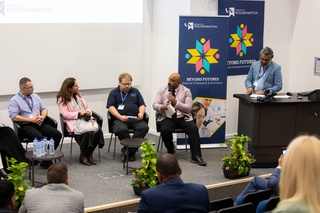 Conference panel of 5 people discussing research projects during the beyond futures event. The people are sitting on stage in a lecture theatre at City Campus.