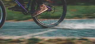 A bicycle riding across a footpath, kicking up dust