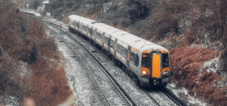 A train crossing through a rural area lightly covered with snow