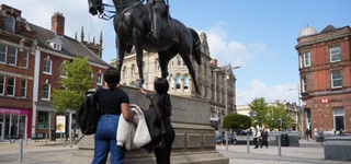 Two students in Wolverhampton city centre inspecting a statue of a man on horseback