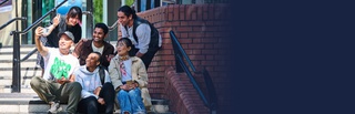 Students sat on the entrance steps of a building while taking a group selfie