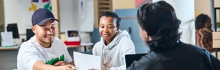 Students sat at desk and speaking with an application advisor